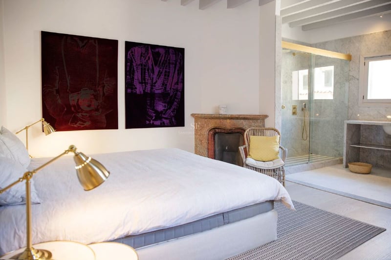Dormitorio principal contemporáneo con chimenea rústica, ducha de mármol integrada y elegantes lámparas de latón.