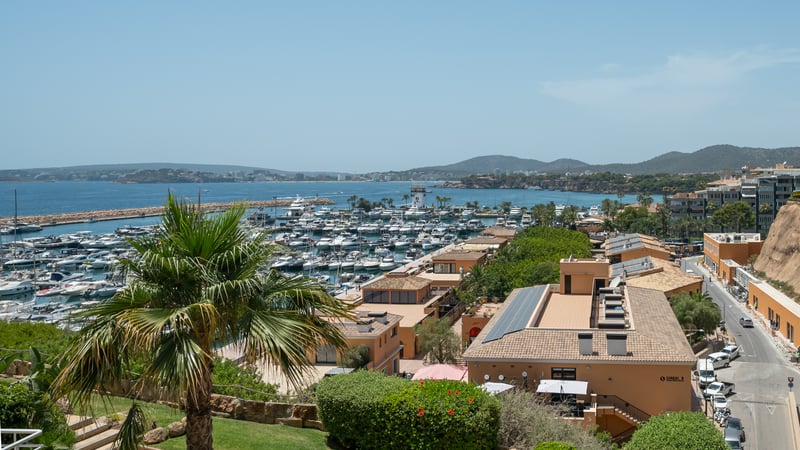 Vue en hauteur d'une marina méditerranéenne remplie de yachts de luxe, surplombant la mer et la côte.