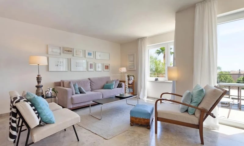 Salon spacieux avec sol en marbre, canapé mauve, touches de bleu et accès direct à une terrasse ensoleillée.