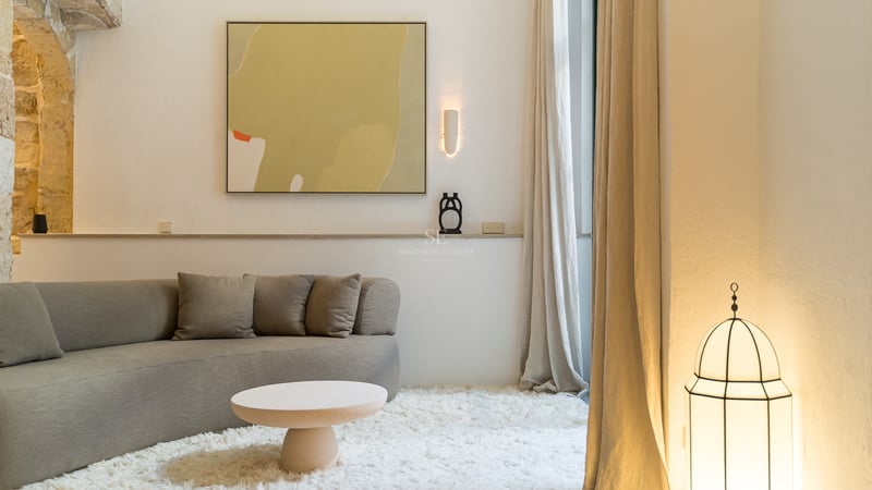 Un salon confortable avec un canapé incurvé gris, un tapis blanc à poils longs et de l'art abstrait.