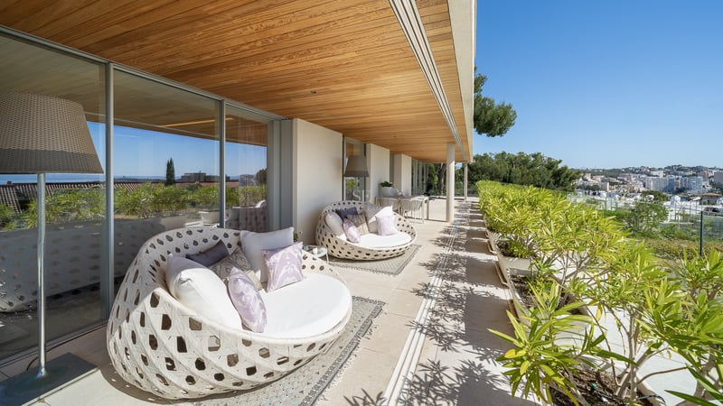 Terrasse ensoleillée avec chaises lounge circulaires en osier, plafond en bois et vue sur le jardin méditerranéen.