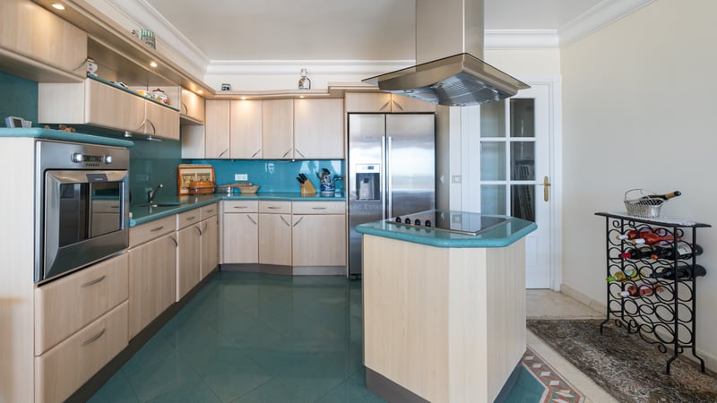 Cuisine contemporaine avec placards en bois clair, plans de travail turquoise et appareils en acier inoxydable.
