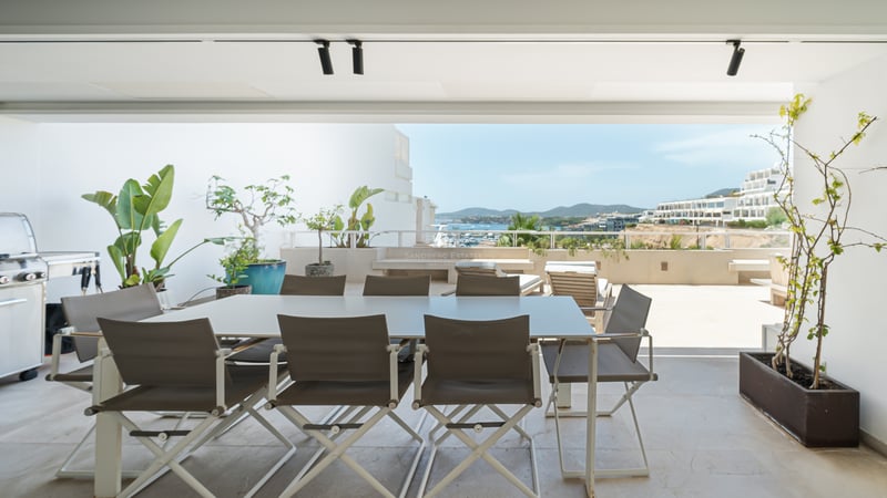 Terrasse moderne avec coin repas, barbecue et vue panoramique sur la côte et la mer.