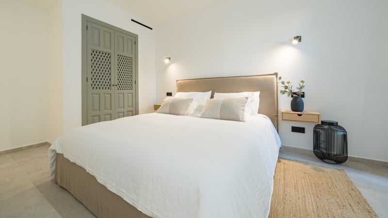 Chambre avec lit double, tête de lit en lin, tables de chevet flottantes en bois et portes de placard vert sauge.