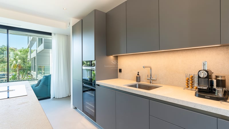 Cuisine contemporaine gris mat avec plan de travail en pierre, appareils intégrés et accès direct à la terrasse.