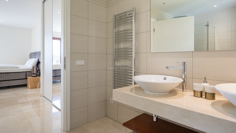 Salle de bains moderne avec doubles vasques, plan de travail en marbre crème et sèche-serviettes chauffant.