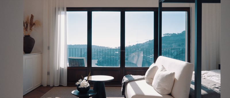 Chambre principale moderne avec canapé blanc, lit à baldaquin et baies vitrées offrant une vue sur la mer.