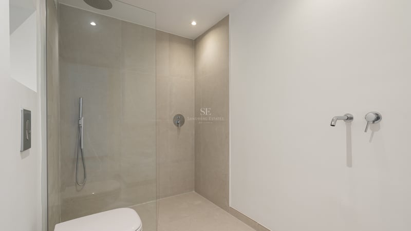 Salle de bain moderne avec douche à l'italienne, paroi en verre et carrelage beige grand format.