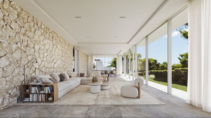 Salon lumineux avec baies vitrées toute hauteur, mur en pierre apparente et mobilier moderne de couleur crème.