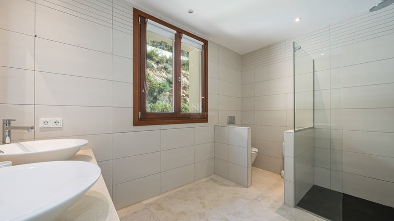 Salle de bain moderne avec doubles vasques, douche vitrée au sol en ardoise et fenêtre en bois.