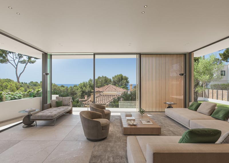 Salon moderne avec baies vitrées, canapés beiges, table en bois et vue sur la mer et les arbres.