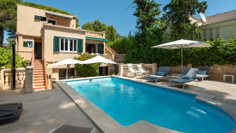 Piscine privée aux eaux turquoises entourée d'une terrasse en pierre et d'une villa méditerranéenne ocre.