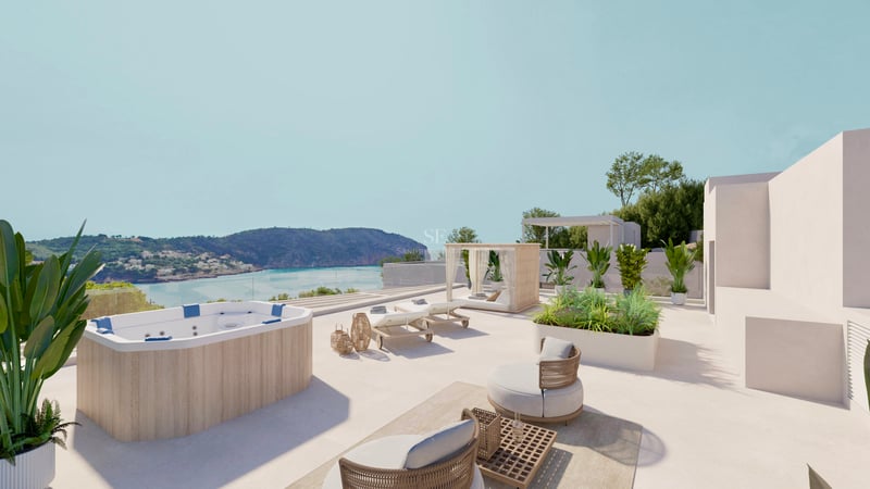 Terrasse ensoleillée avec jacuzzi en bois, transats et fauteuils surplombant une baie côtière.