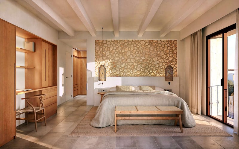 Chambre de luxe avec mur en pierre, poutres apparentes, bureau intégré en bois et porte-fenêtre.