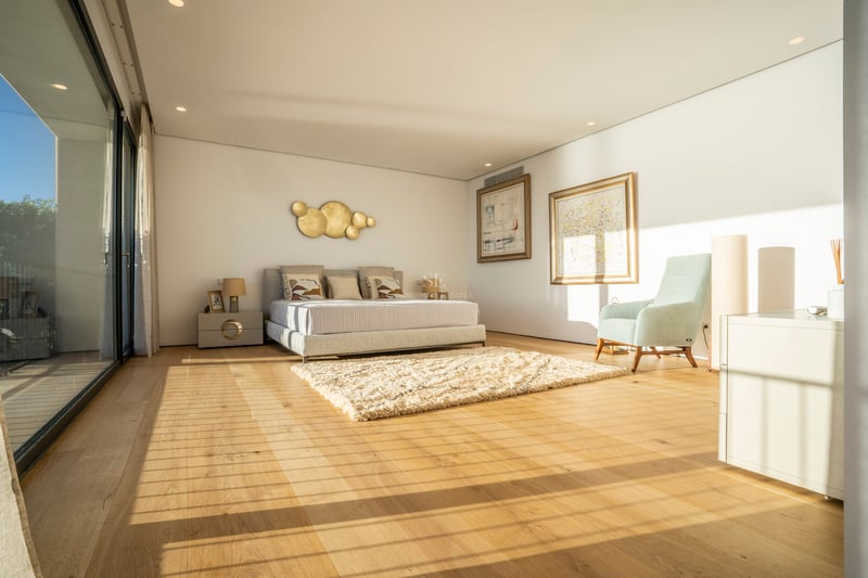 Chambre principale moderne et lumineuse avec parquet en chêne, baies vitrées et mobilier contemporain.