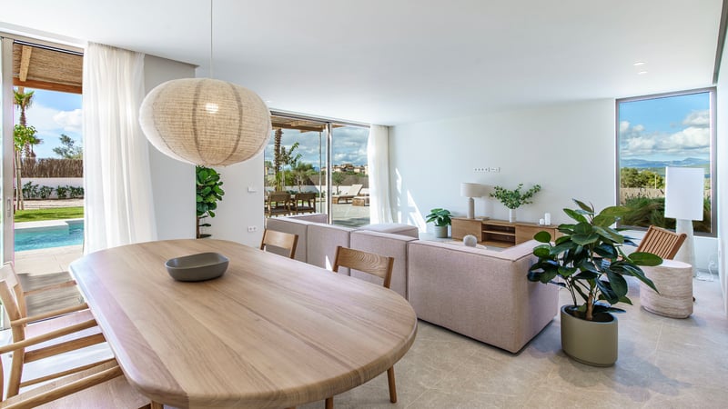 Salon et salle à manger modernes avec mobilier en chêne, canapé en tissu et baies vitrées donnant sur la piscine.