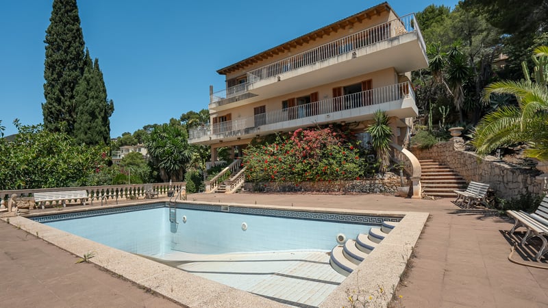 Grande piscine privée devant une villa méditerranéenne de trois étages avec terrasses et jardins luxuriants.
