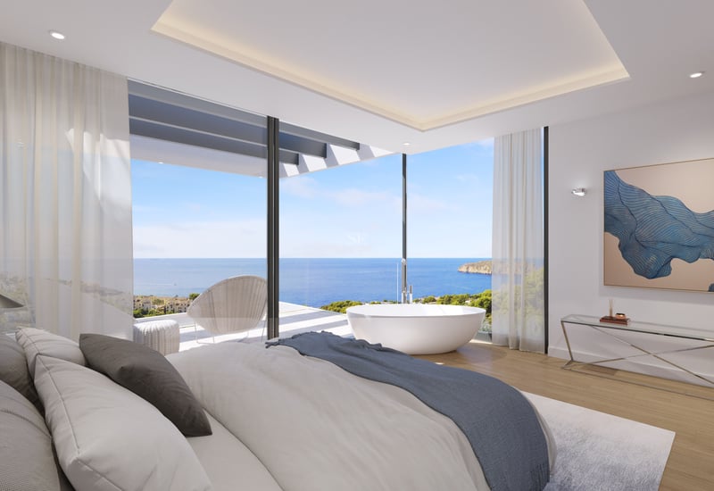 Chambre de luxe avec baignoire îlot et baies vitrées d'angle donnant sur la mer Méditerranée.