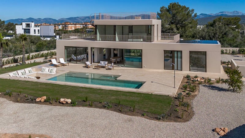 Façade d'une villa contemporaine avec piscine rectangulaire, grande terrasse en pierre et baies vitrées.
